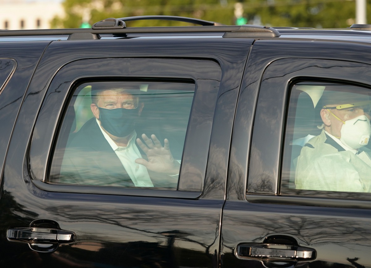US President Trump waves from the back of a car in a motorcade outside of Walter Reed Medical Center in Bethesda, Maryland on Ocotber 4, 2020. / AFP / ALEX EDELMAN
