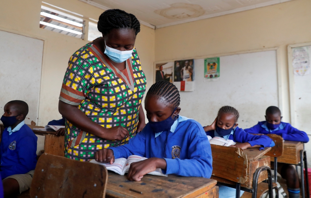 School teacher Elizabeth Nyabwa attends to a student inside a classroom at the Olympic Primary School during the partial reopening of schools, after the government scrapped plans to cancel the academic year due to the coronavirus disease (COVID-19) pandem