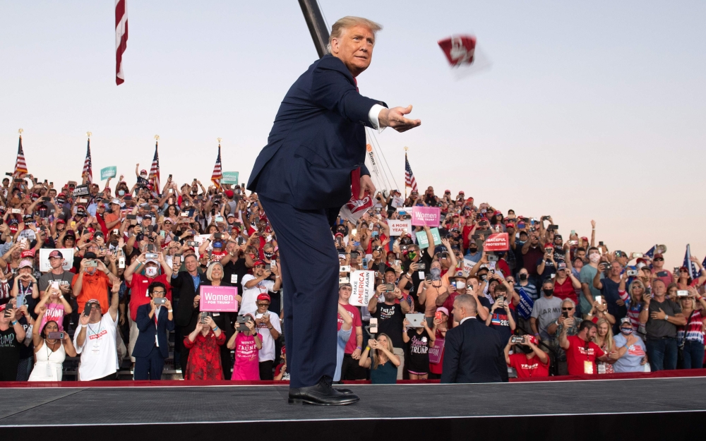 US President Donald Trump throws masks to supporters as he arrives to hold a Make America Great Again rally as he campaigns at Orlando Sanford International Airport in Sanford, Florida, October 12, 2020. AFP / SAUL LOEB