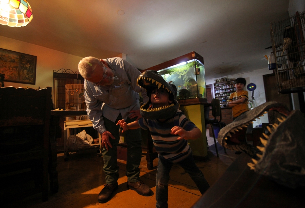 Alonso Toro, a professional musician who worked in television and advertising, looks at his son Elias who wears a dinosaur face mask made by him, during the coronavirus disease (COVID-19) pandemic, in Caracas, Venezuela August 26, 2020. Reuters/Fausto Tor