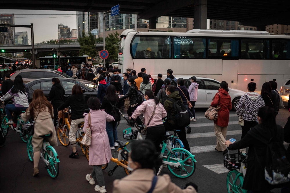 People try to pass through traffic as they commute with shared bicycles during rush hour in Beijing on October 14, 2020. / AFP / NICOLAS ASFOURI