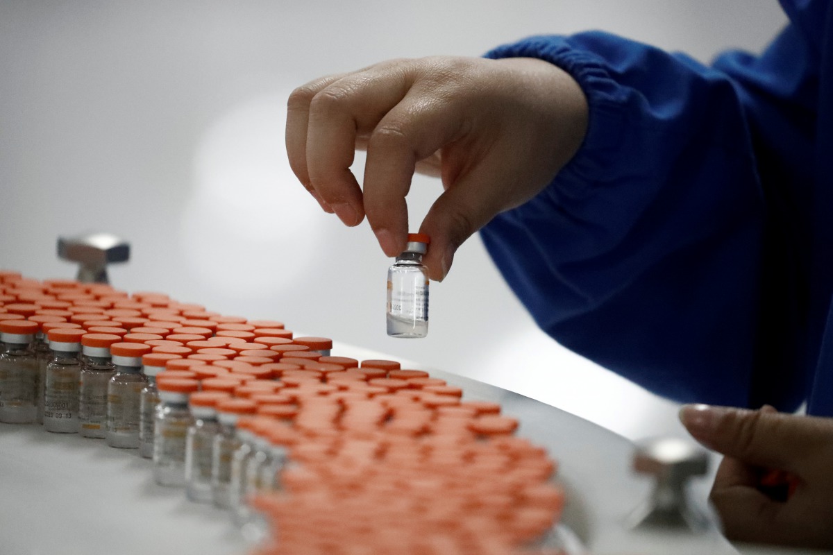 FILE PHOTO: A worker performs a quality check in the packaging facility of Chinese vaccine maker sinovac Biotech, developing an experimental coronavirus disease (COVID-19) vaccine, during a government-organized media tour in Beijing, China, September 24, 