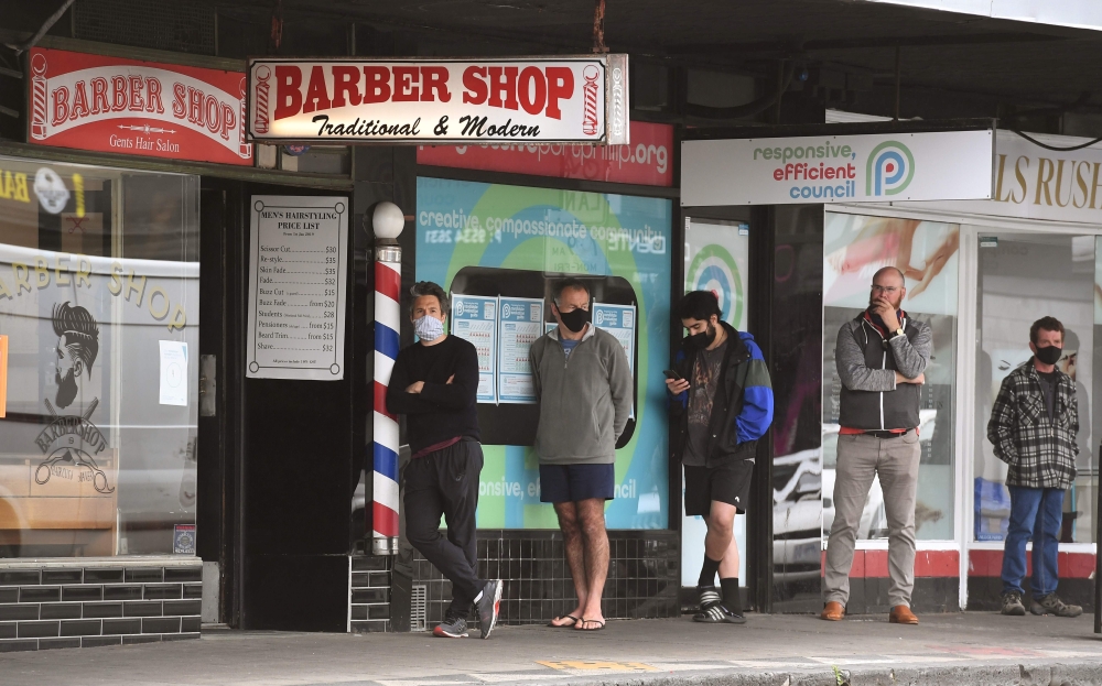 Men queue for a haircut outside a barber shop in Melbourne on October 19, 2020, as some of the city's three-month-old stay-at-home restrictions due to the COVID-19 coronavirus outbreak were further eased on falling infection rates. / AFP / William WEST