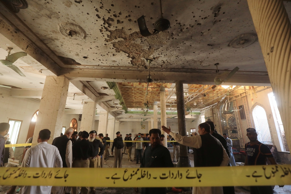 Police officers and officials survey the site of a bomb blast at a religious seminary in Peshawar, Pakistan October 27, 2020. Reuters/Fayaz Aziz
 