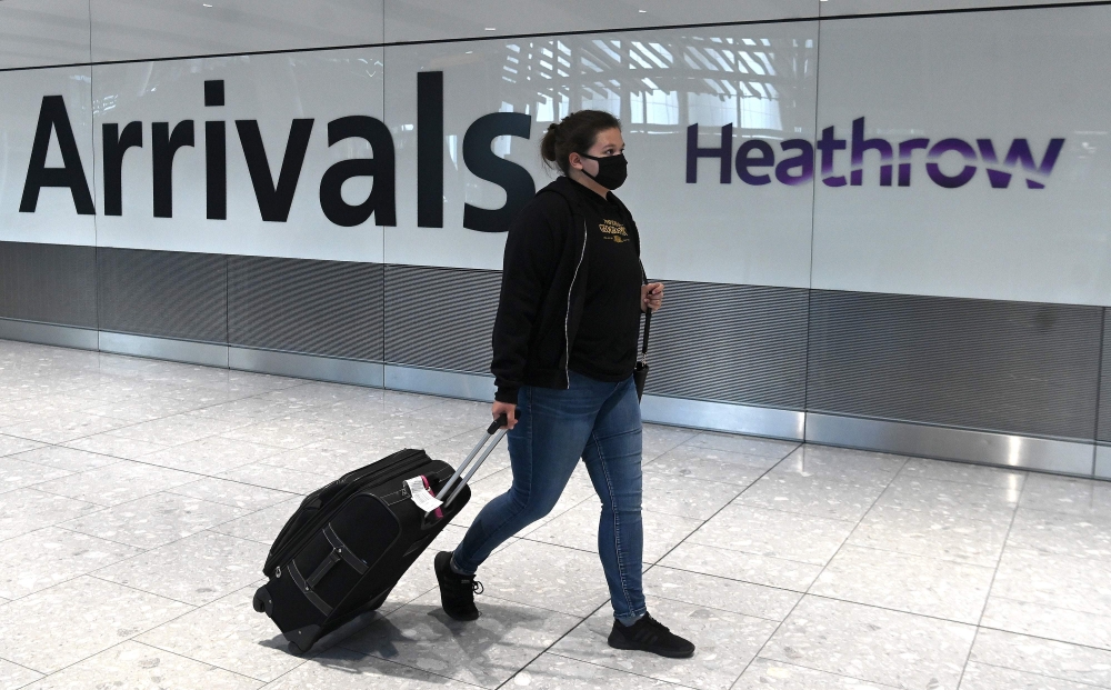 FILES) In this file photo taken on July 10, 2020 passengers wearing a face mask or covering due to the COVID-19 pandemic, arrive at Heathrow airport, west London. AFP / DANIEL LEAL-OLIVAS
