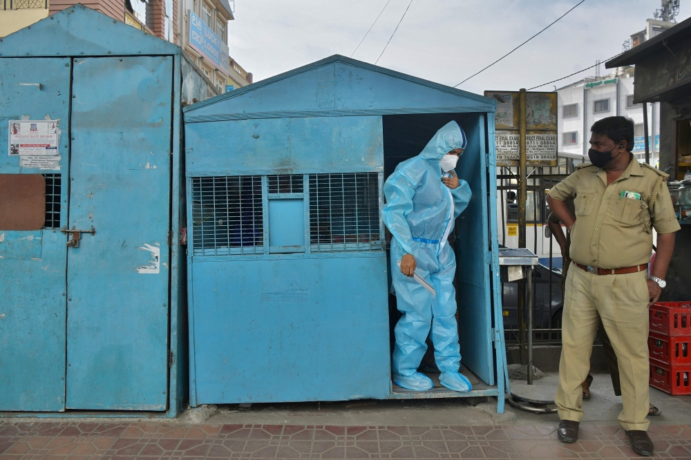 A health worker wearing protective gear prepares to conduct swab tests on people at a mobile Covid-19 coronavirus testing clinic at a bus stand in Bangalore on October 29, 2020. / AFP / Manjunath Kiran