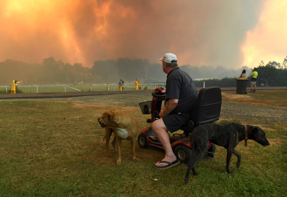 (FILES) A file photo was taken on November 12, 2019 shows locals watching as bushfires impact on farmland near the small town of Nana Glen, some 600kms north of Sydney. / AFP / William WEST

