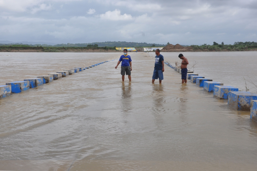 Residents wade in a flooded bridge over a swollen river due to heavy rains in Ilagan town, Isabela province north of Manila on October 31, 2020, ahead of Typhoon Goni's landfall in the Philippines. / AFP / Villamor Visaya