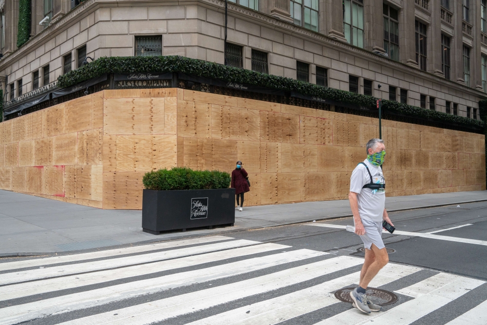 A person walks by a boarded-up Saks Fifth Avenue on November 1, 2020, in New York City. Businesses have taken to boarding up storefronts in anticipation of unrest related to the presidential election. David Dee Delgado/Getty Images/AFP 