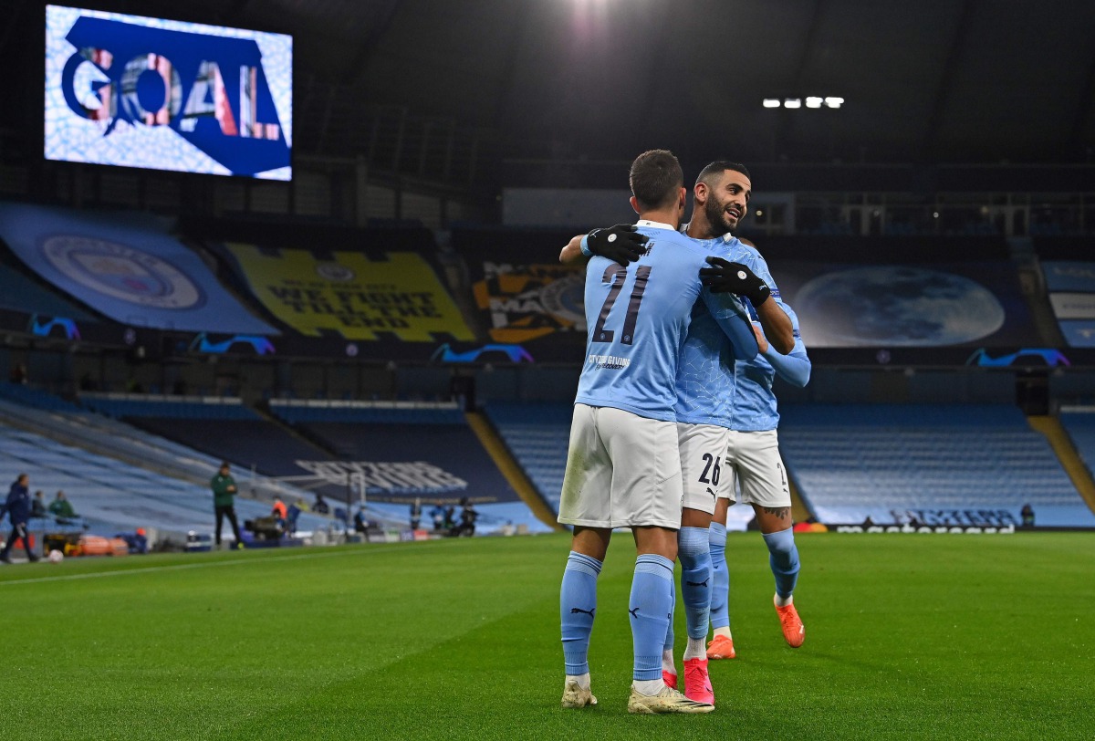 Manchester City's Spanish midfielder Ferran Torres (L) celebrates scoring the opening goal with Manchester City's Algerian midfielder Riyad Mahrez during the UEFA Champions League football Group C match between Manchester City and Olympiakos at the Etihad