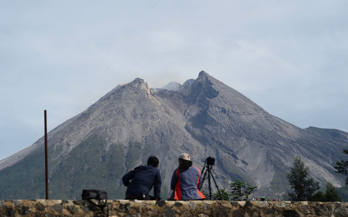 Photographers keep an eye on Mount Merapi in Yogyakarta on November 6, 2020 as Indonesia Geological agency raised the status of alert for Merapi to the second highest ahead of upcoming major eruption. / AFP / Agung Supriyanto
