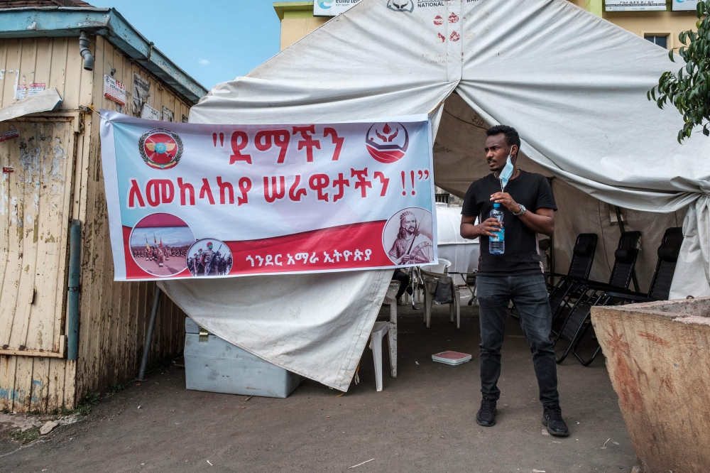 A man stands next to a sign at a blood donation station, calling for blood donation for the Ethiopian Defence Forces in the city of Gondar, Ethiopia, on November 06, 2020.  AFP / EDUARDO SOTERAS