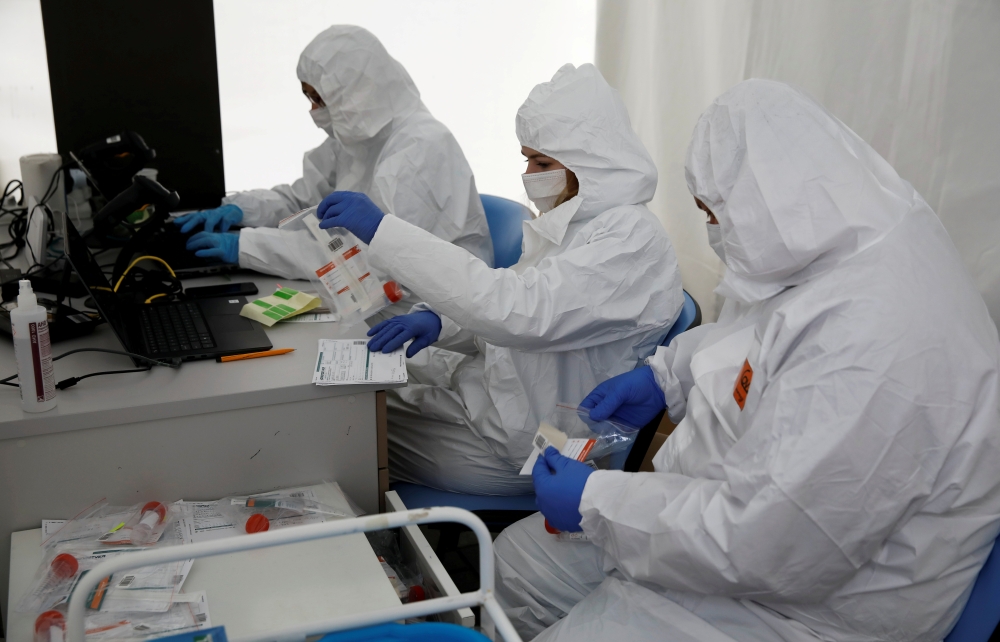 FILE PHOTO: People wearing protective coverall work at the drive-thru testing centre on the coronavirus disease (COVID-19) in Warsaw, Poland, October 2, 2020. REUTERS/Kacper Pempel