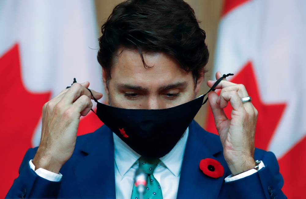 Canadian Prime Minister Justin Trudeau puts on a mask at a news conference held to discuss the country's coronavirus disease (COVID-19) response in Ottawa, Ontario, Canada. November 6, 2020. REUTERS/Patrick Doyle