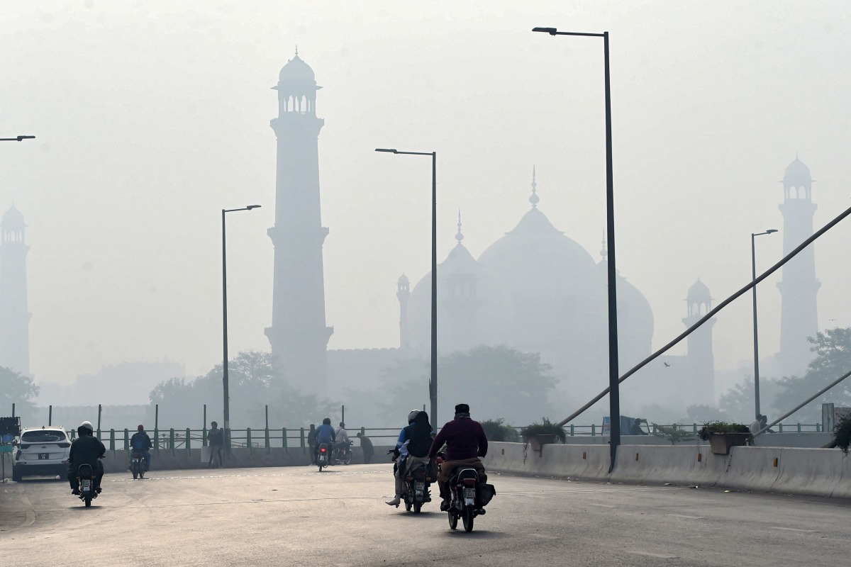Motorcyclists ride on a bridge amid heavy smoggy conditions in Lahore on November 10, 2020. / AFP / Arif ALI
