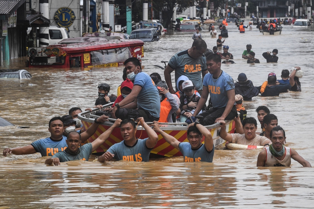 Rescuers pull a rubber boat carrying residents through a flooded street after Typhoon Vamco hit in Marikina City, suburban Manila on November 12, 2020. / AFP / Ted ALJIBE