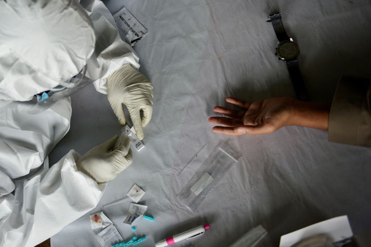 TOPSHOT - An Indonesian military health staff takes a blood sample to test for the COVID-19 coronavirus during a mass testing at a playground in Banda Aceh on November 7, 2020. / AFP / CHAIDEER MAHYUDDIN

