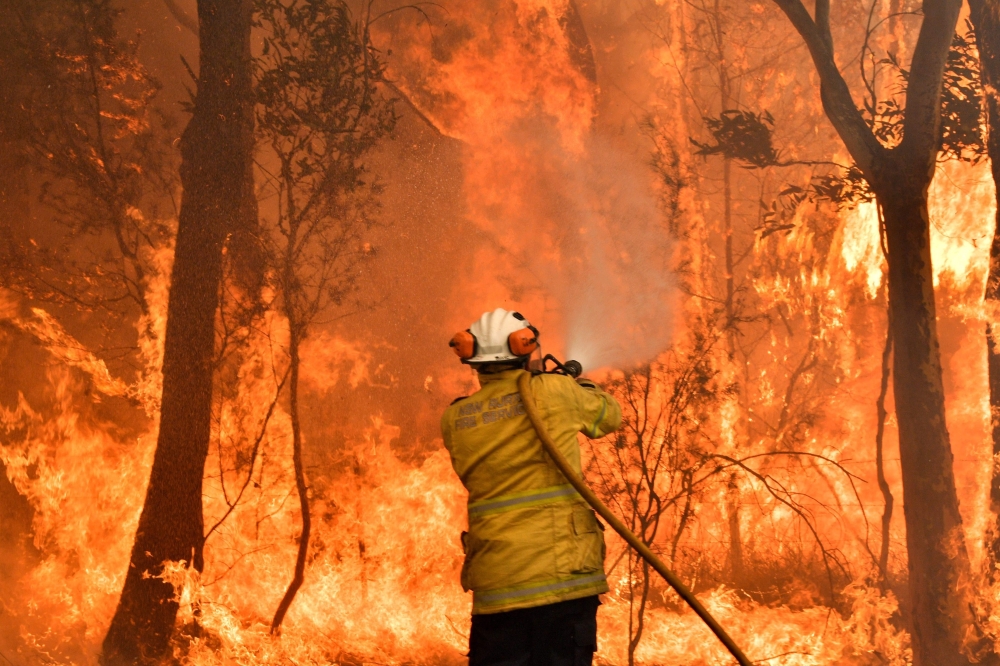 This file photo taken on December 10, 2019 shows a firefighter conducting back-burning measures to secure residential areas from encroaching bushfires in the Central Coast, some 90-110 kilometres north of Sydney. / AFP / Saeed KHAN