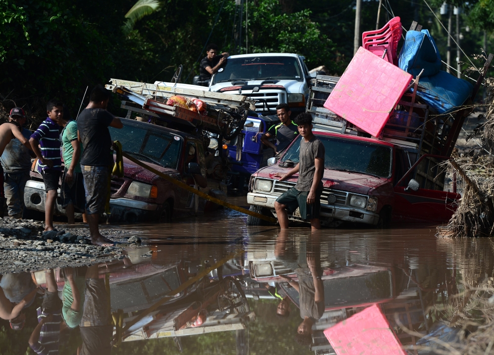 Workers of banana fields come across a flooded road while evacuating the area in El Progreso, Yoro department, Honduras, on November 14, 2020, before the arrival of tropical storm Iota. Less than two weeks after powerful storm Eta killed more than 200 peo