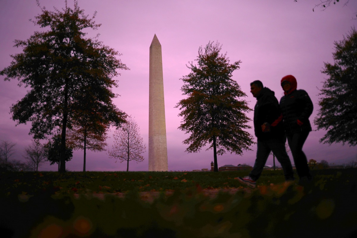 People walk past the Washington monument at sunset in Washington, U.S., November 12, 2020. REUTERS/Hannah McKay
