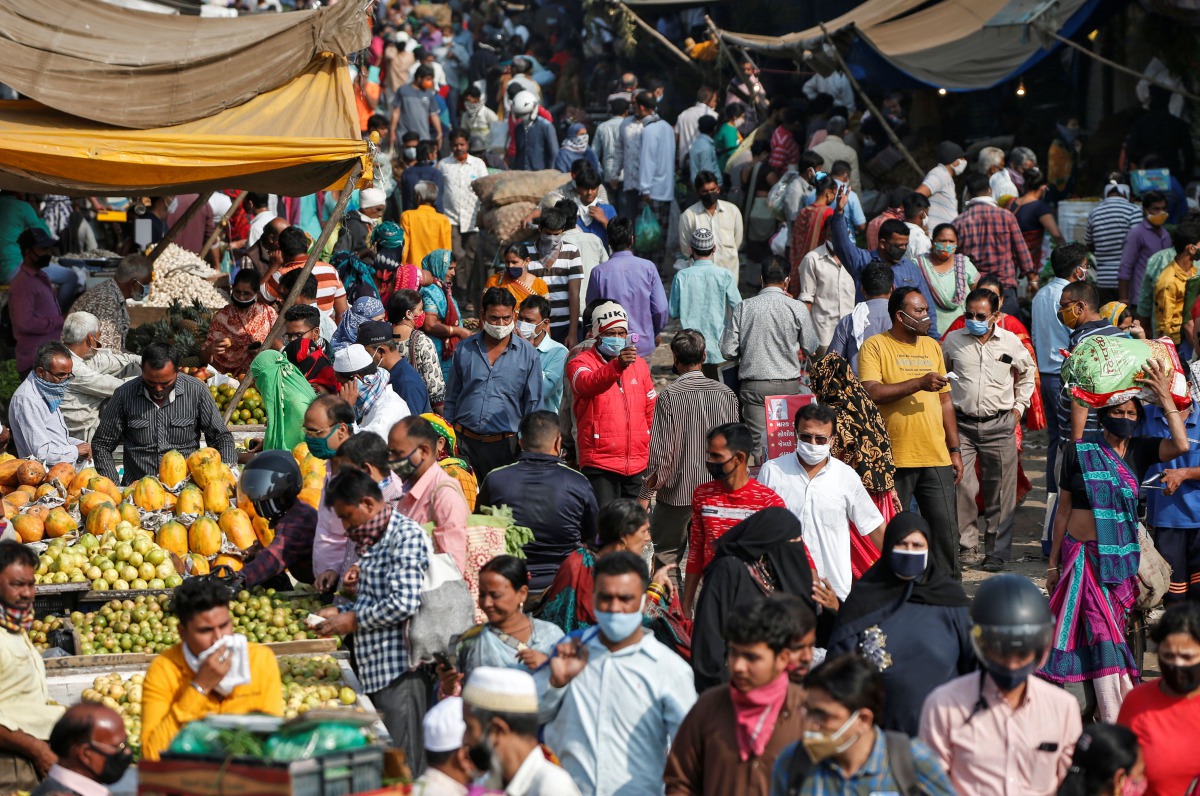 A health worker takes the temperature of shoppers at a crowded market amid the spread of the coronavirus disease (COVID-19), in Ahmedabad, India, November 20, 2020. REUTERS/Amit Dave
