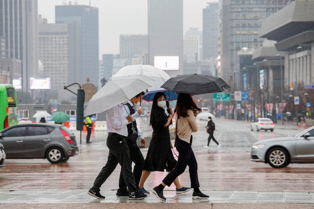 Pedestrians wearing masks walk with umbrellas as it rains amid the coronavirus disease (COVID-19) pandemic in central Seoul, South Korea, November 19, 2020. REUTERS/Heo Ran