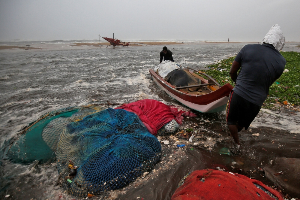 Fishermen move a fishing boat to a safer place along the shore before Cyclone Nivar's landfall, in Chennai, India, November 25, 2020. REUTERS/P. Ravikumar