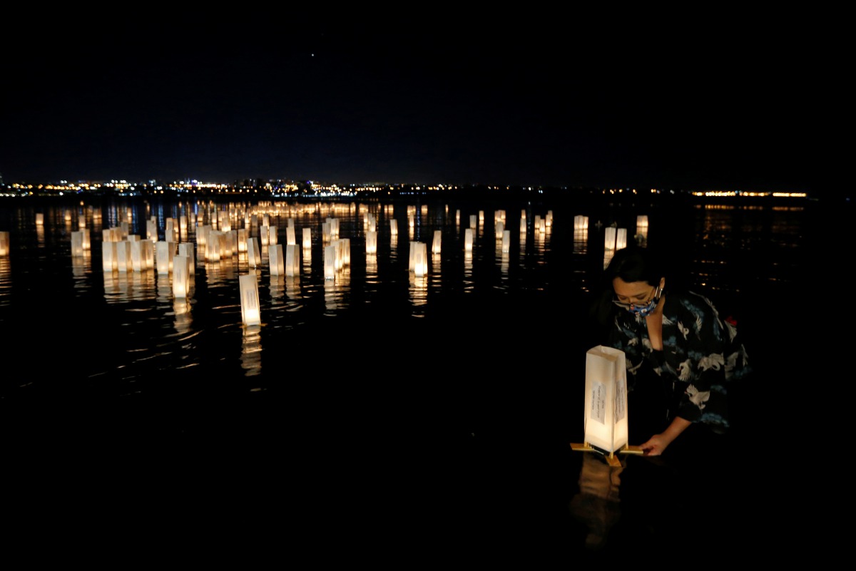 A woman sets afloat lanterns on the water during the Japanese ceremony 