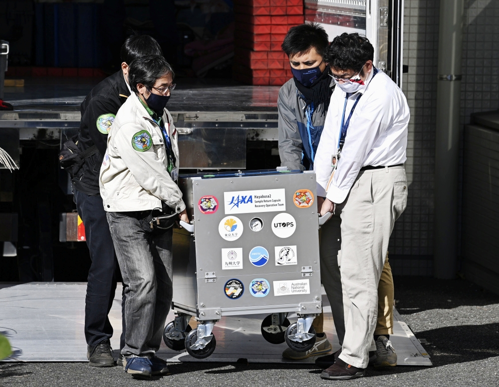 Japan Aerospace Exploration Agency's (JAXA) staff carry a case containing Hayabusa2's capsule with extensive samples of an asteroid as it arrives at JAXA Sagamihara Campus in Sagamihara in this photo taken by Kyodo December 8, 2020. Mandatory credit Kyodo