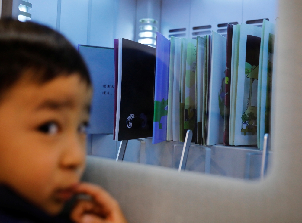 A boy looks at an ultraviolet sterilising machine cleaning library books he rents, amid the coronavirus disease (COVID-19) outbreak, at Narimasu library in Itabashi district in Tokyo, Japan, December 9, 2020. REUTERS/Kim Kyung-Hoon