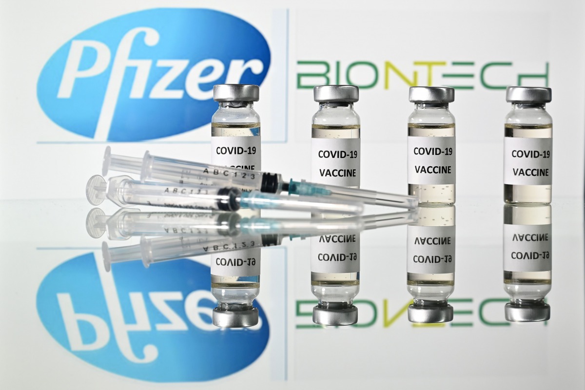 (FILES) This file illustration taken on November 17, 2020, in London shows vials with Covid-19 vaccine stickers attached and syringes with the logo of US pharmaceutical company Pfizer and German partner BioNTech. Canada on December 9, 2020, approved the P