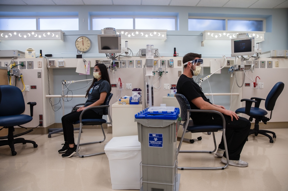 Kassandra Martinez (L), an EVS Attendant and Lead waits for Rachel Marrs (out of frame) to administer the Pfizer-BioNTech Covid-19 Vaccine shot at Rady Children's Hospital in San Diego, California on December 15, 2020. / AFP / ARIANA DREHSLER