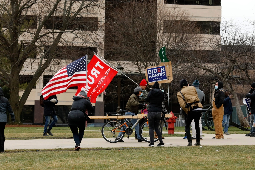 Supporters of President Donald Trump and a supporter of President-elect Joe Biden stand outside the Michigan state capital as the Electoral College votes in Lansing, Michigan on December 14, 2020.  AFP / JEFF KOWALSKY