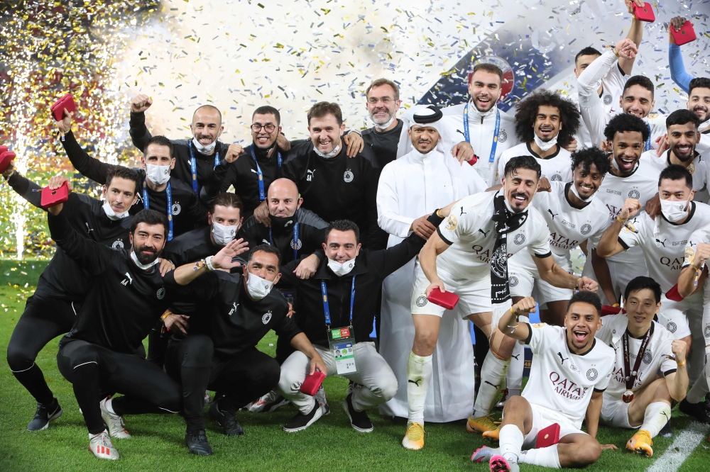 Al Sadd's coach Xavi Hernandez (centre) poses for a group picture with his players as they celebrate after Al Sadd won the Amir Cup final football match against Al Arabi on December 18, 2020. / AFP / KARIM JAAFAR
