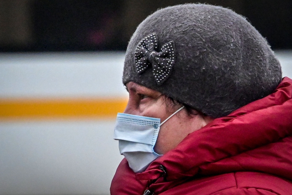 A woman wearing a face mask to protect against the coronavirus disease walks along a street in the town of Chekhov, some 70 km outside Moscow, on December 21, 2020. / AFP / Yuri KADOBNOV