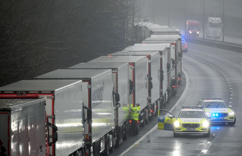 Police officers speak to a driver in one of lorries parked on the M20 motorway towards Eurotunnel and the Port of Dover, as EU countries impose a travel ban from the UK following the coronavirus disease (COVID-19) outbreak, in Folkestone, Britain, Decembe