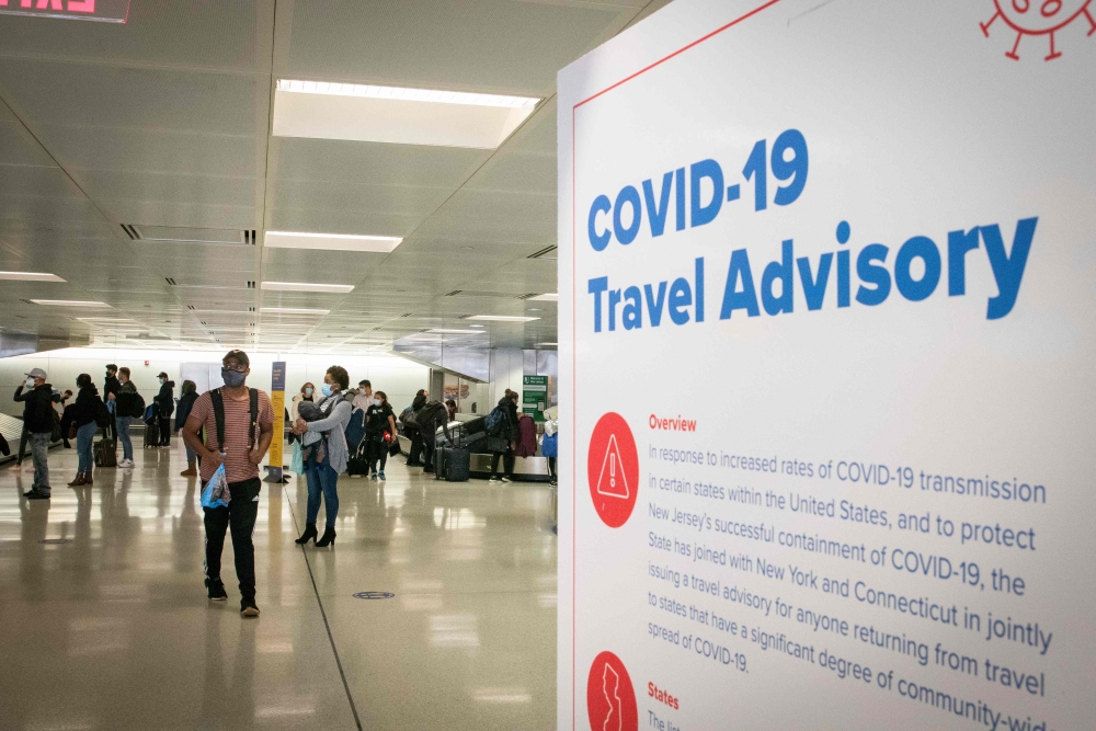 (FILES) In this file photo taken on November 21, 2020 travelers wait for their luggage at Newark International Airport in Newark, New Jersey. AFP / Kena Betancur