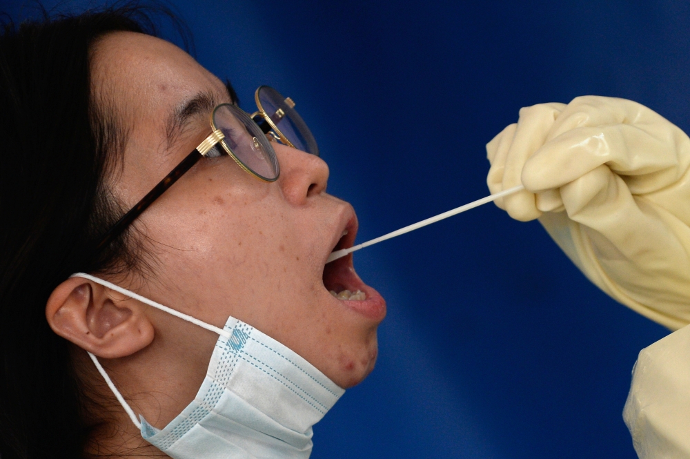 A woman undergoes a swab test amid the coronavirus disease (COVID-19) pandemic at a testing station, in Makati City, Metro Manila, Philippines, December 21, 2020. REUTERS/Lisa Marie David