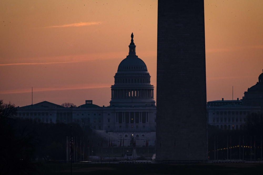 The U.S. Capitol Building is seen past the Washington Monument as the sun rises on December 27, 2020 in Washington, DC. Samuel Corum/Getty Images/AFP