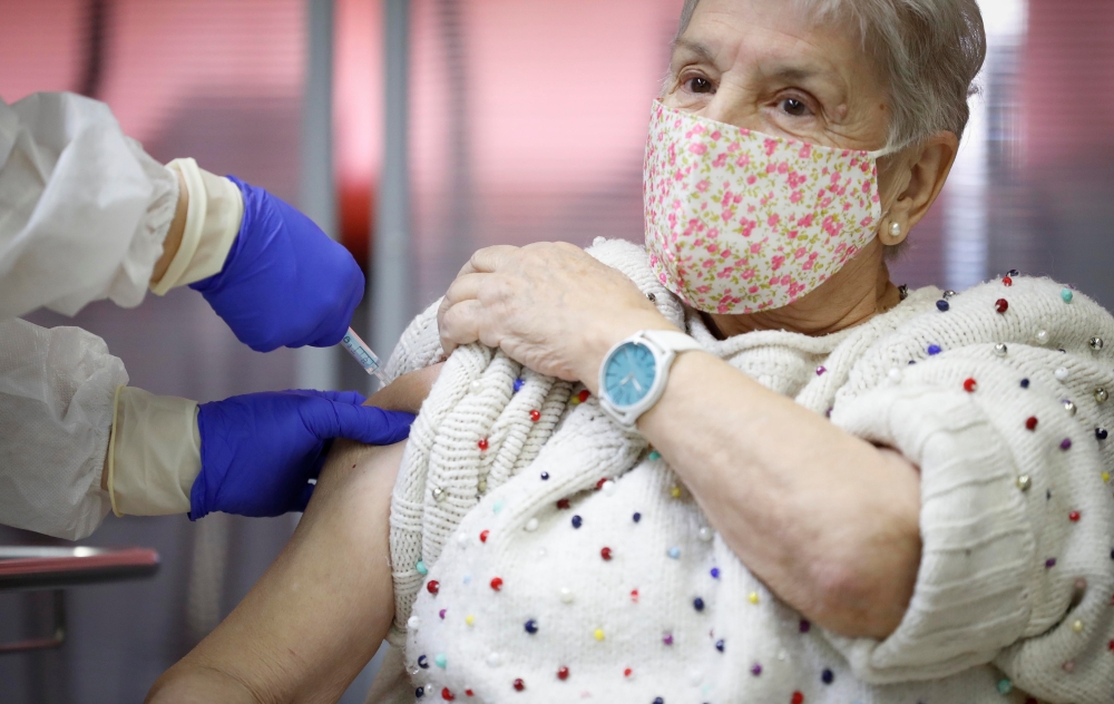 An elderly woman receives an injection with a dose of Pfizer-BioNTech Covid-19 vaccine at Vallecas nursing home, as the coronavirus disease (COVID-19) outbreak continues, in Madrid, Spain December 27, 2020. Comunidad de Madrid/Handout via Reuters