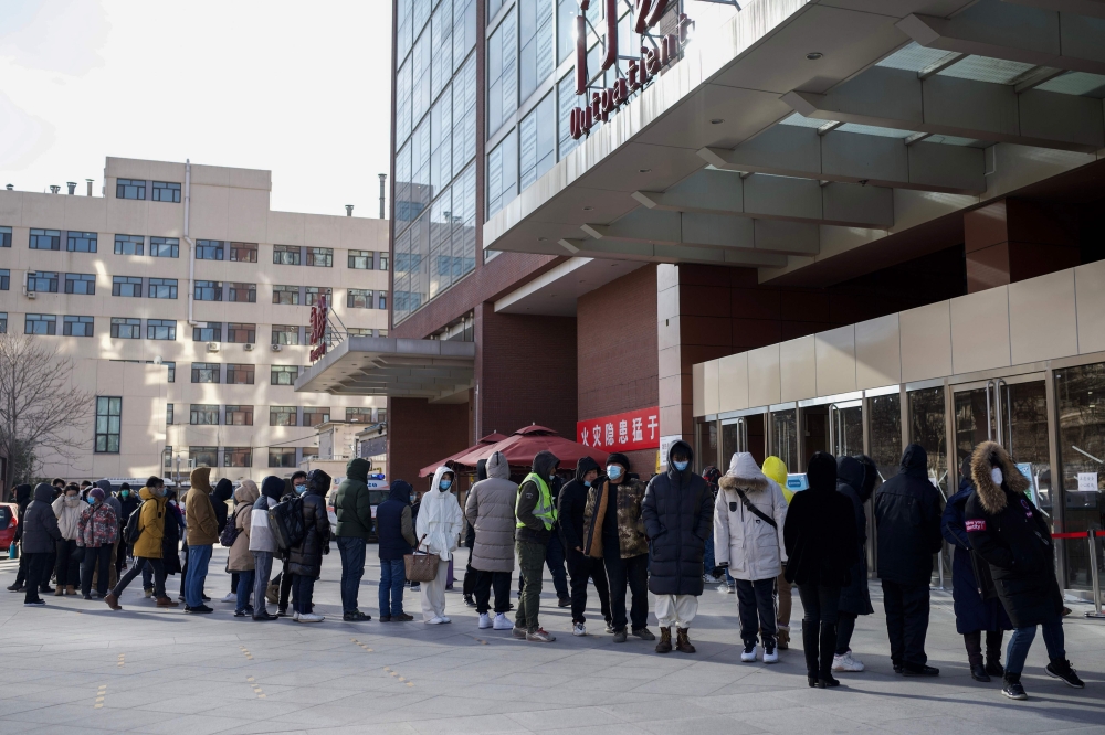Residents wearing face masks wait in a queue to be tested for the Covid-19 coronavirus in Beijing on December 29, 2020. / AFP / Noel Celis