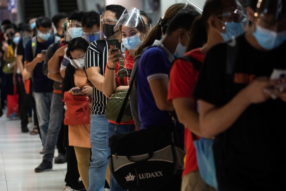 Passengers wearing face masks and face shields for protection against the coronavirus disease (COVID-19) queue for bus rides going to provinces amid the holiday season, at the Paranaque Integrated Terminal Exchange, in Paranaque City, Metro Manila, Philip