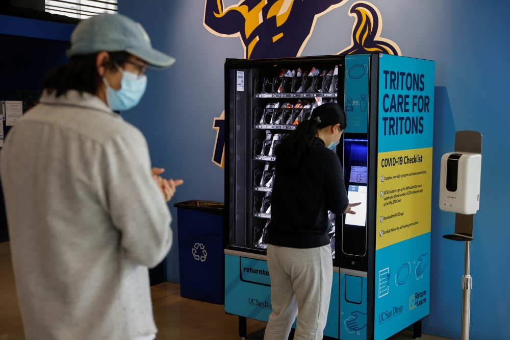 People wearing masks queue up at a vending machine, placed by UC San Diego on campus for students and teachers to self-administer COVID-19 tests, during the outbreak of the coronavirus disease (COVID-19) in San Diego, California, U.S., January 5, 2021. Re