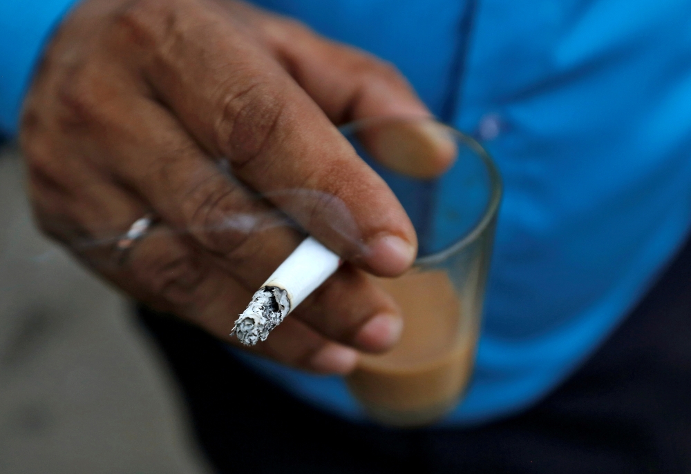 FILE PHOTO: A man smokes a cigarette along a road in Mumbai, India, October 26, 2016. REUTERS/Danish Siddiqui