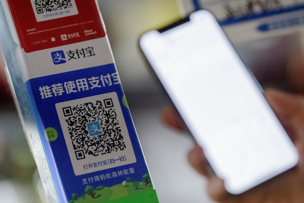 Customer uses a phone to scan the QR code of the electronic payment service alipay that belongs to Ant Group Co Ltd at a market stall in Beijing, China, December 31, 2020. REUTERS/Thomas Peter
