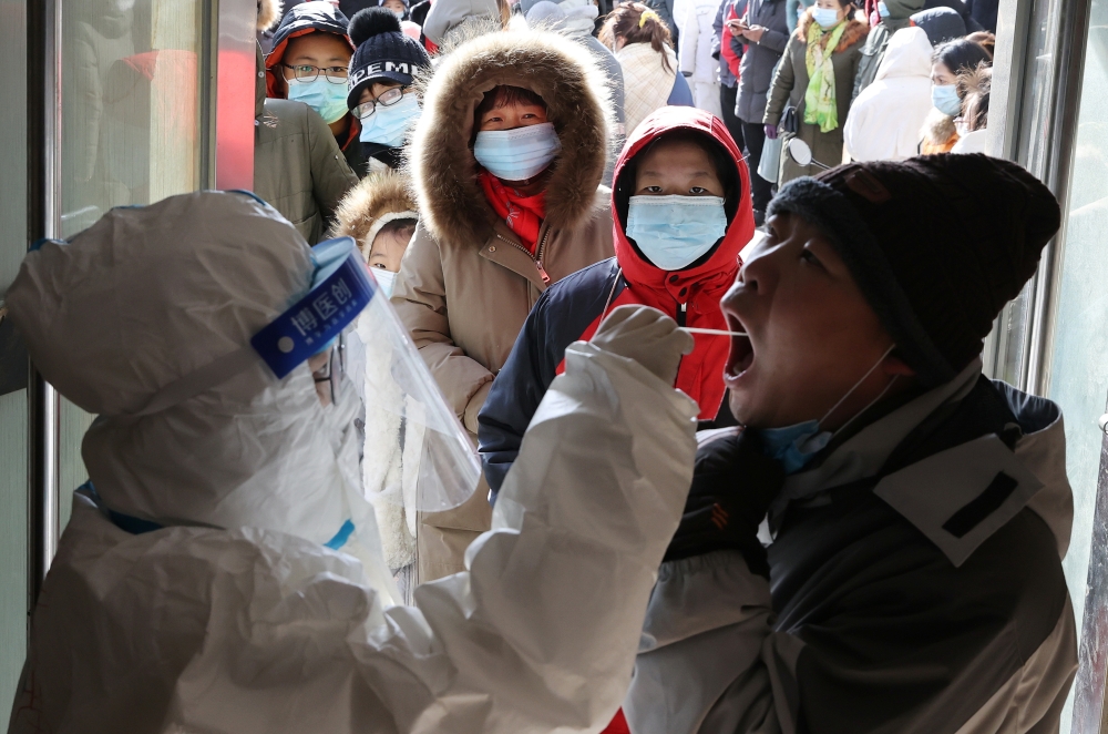 A medical worker in protective suit collects a swab from a resident following a recent coronavirus disease outbreak in Shijiazhuang, Hebei province, China January 6, 2021. China Daily via Reuters