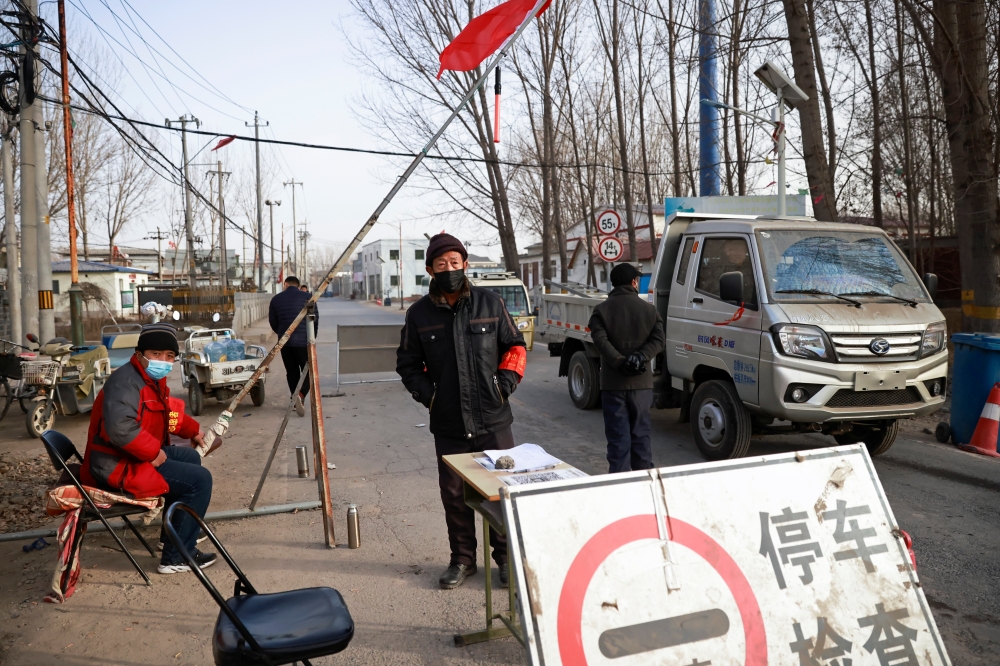 Volunteers stand at a checkpoint on a road leading into their village, following the coronavirus disease (COVID-19) outbreak, on the outskirts of Beijing near the provincial border with Hebei province, China January 12, 2021. REUTERS/Thomas Peter