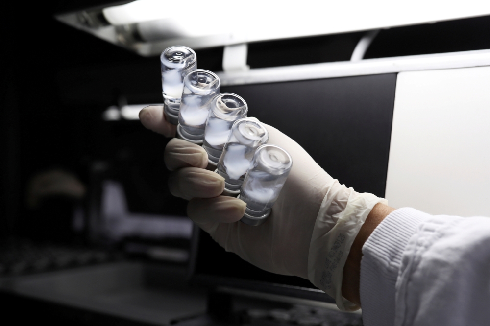 An employee inspects vials containing CoronaVac, Sinovac Biotech's vaccine against the coronavirus disease (COVID-19), at Butantan biomedical center in Sao Paulo, Brazil, January 12, 2021. REUTERS/Amanda Perobelli/File Photo
