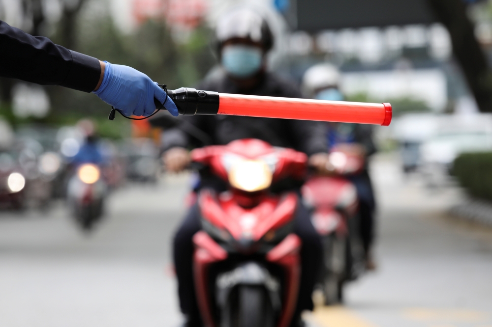 A police officer stops a rider at a roadblock as he enforces a lockdown due to the coronavirus disease (COVID-19) outbreak, in Kuala Lumpur, Malaysia January 13, 2021. Reuters/Lim Huey Teng