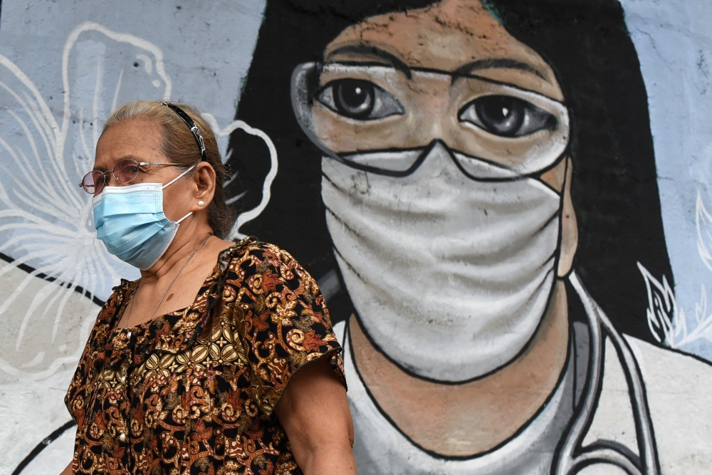 A woman wearing a face mask as protection against the coronavirus disease (COVID-19) walks past a mural dedicated to frontline workers, in Manila, Philippines, January 11, 2021. REUTERS/Lisa Marie David